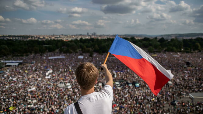 Un checo ondea una bandera mientras observa la multitudinaria protesta en el parque de Letná en Praga.