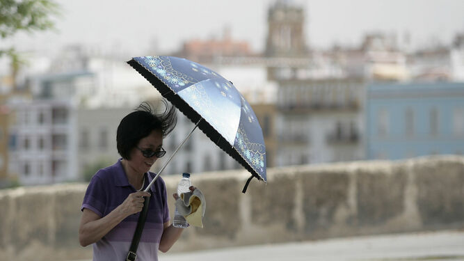 Una turista se cubre del sol con un paraguas.