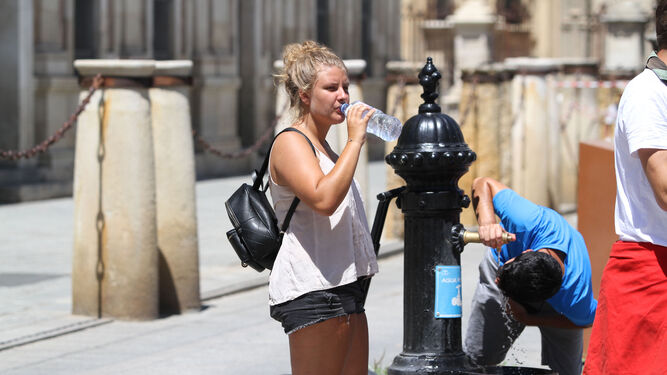 Turistas beben agua en una fuente pública en Sevilla.