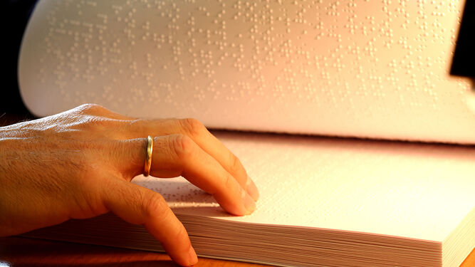 Un socio de la ONCE lee un libro en braille.
