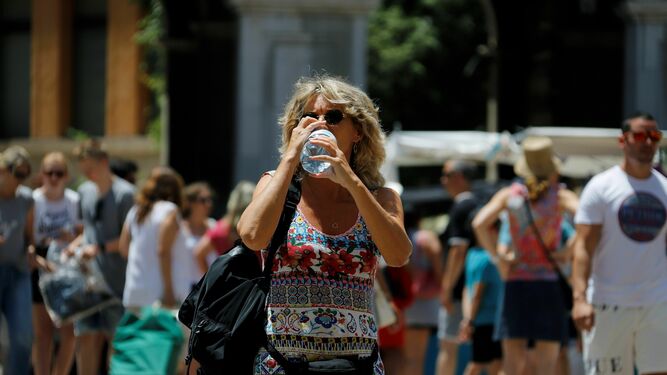 Un mujer se refresca bebiendo agua en la calle.