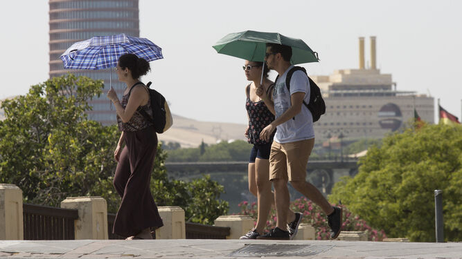 Jóvenes paseando por Sevilla con paraguas para protegerse del calor.jpg