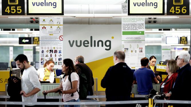 Un grupo de pasajeros ante un mostrador de facturacion de Vueling en el Aeropuerto de Barcelona-El Prat.