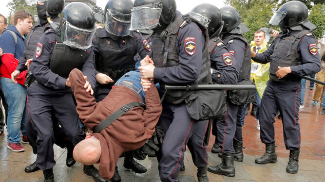 Varios agentes de la policía rusa detienen a uno de los manifestantes.
