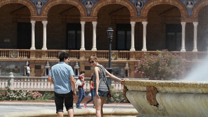 Dos jóvenes se refrescan en la fuente de la Plaza de España.