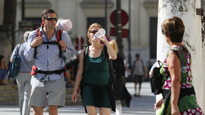 Turistas se hidratan bebiendo agua un día de calor en Sevilla