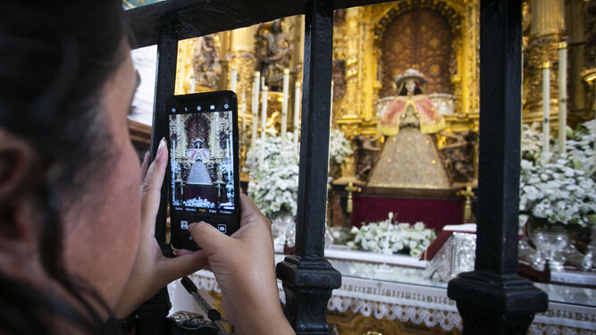 Un devoto realiza una foto con el móvil de la Virgen del Rocío con sus galas de pastora.