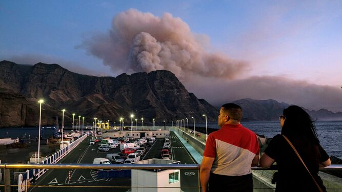 Una pareja observa la columna de humo reactivada en el Pinar de Tamadaba, en Gran Canaria.