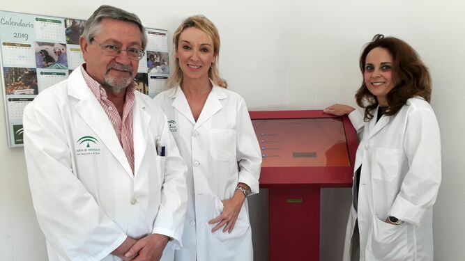 Las doctoras Amalia Pérez Gil y Raquel Hernández y el enfermero Francisco Reche posan  junto al Totem, una herramienta utilizada para el cribado de psoriasis en pacientes.