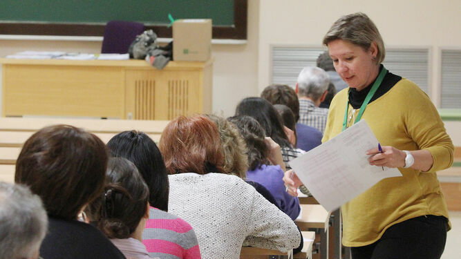 Una examinadora reparte exámenes en una oposición en Sevilla