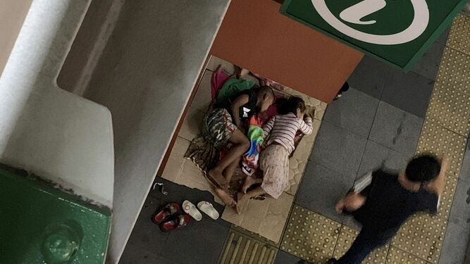 Niños mendicantes duermen bajo una parada de tren elevado en Bangkok.