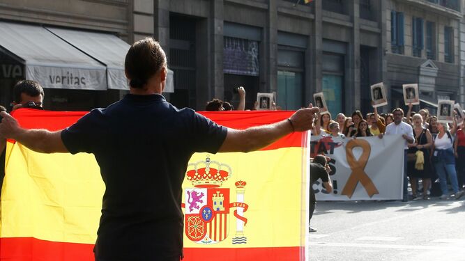 Un hombre con una bandera de España se encara con los centenares de personas que cortan la céntrica Via Laietana de Barcelona.