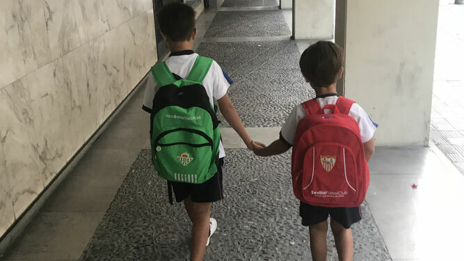 Pepe y Jesús Camacho, con sus mochilas del Betis y del Sevilla FC, de la mano por Los Remedios.