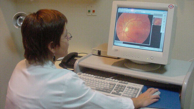 Una oftalmóloga estudia  una retinografía en su ordenador.