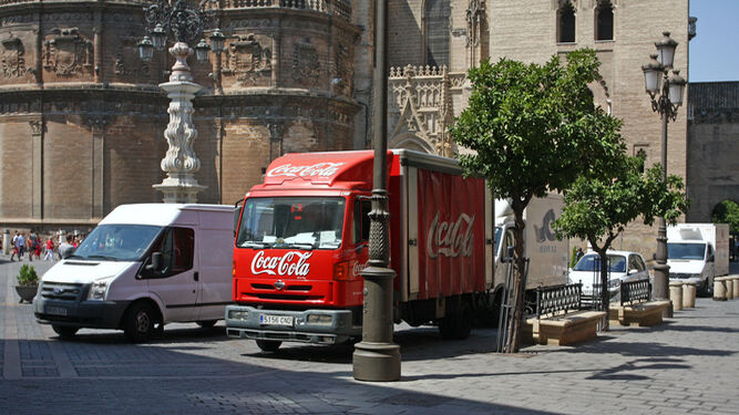 Varios vehículos de transporte de mercancías estacionados en la Plaza Virgen de los Reyes ante la Catedral.
