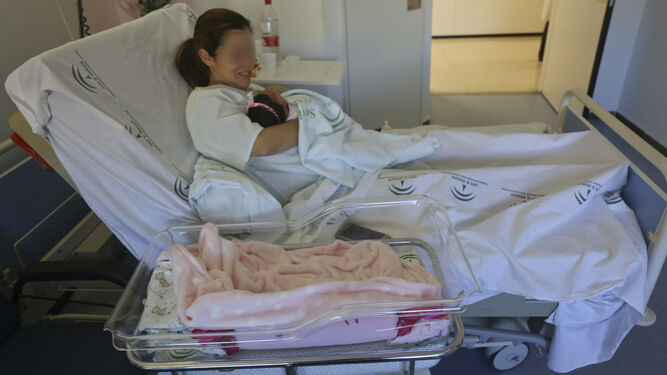 Una mujer con su bebé recién nacido por cesárea en la cama de un hospital.