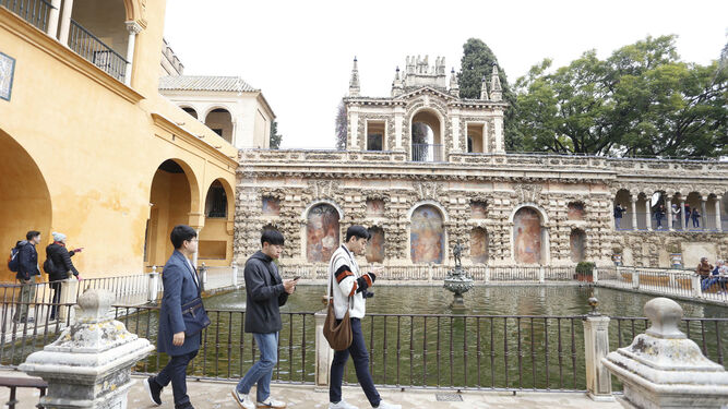 Turistas pasean ante el Estanque de Mercurio del Real Alcázar.