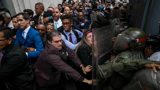 Juan Guaidó (izquierda), líder opositor venezolano, es agarrado mientras opositores forcejean con la Guardia Bolivariana para entrar ayer en la Asamblea Nacional.