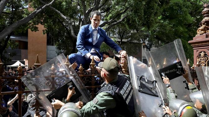 Guaidó, líder opositor a Maduro, se encarama a una verja para tratar de acceder sin éxito al Parlamento.