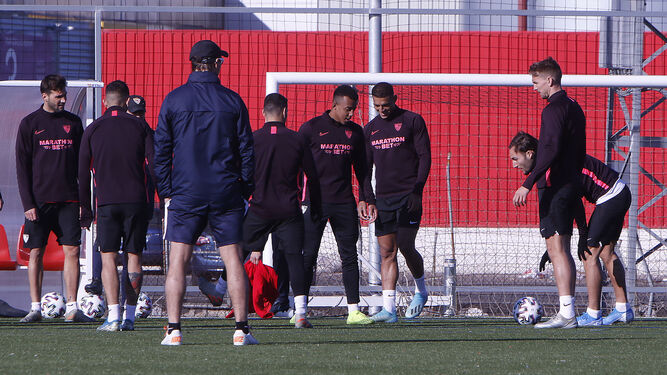 Los futbolistas del Sevilla se ejercitan sobre césped artificial ante la mirada de Lopetegui.