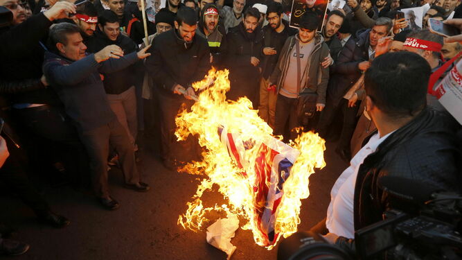 Un grupo de manifestantes quema una bandera del Reino Unido ante la Embajada de este país en Irán.