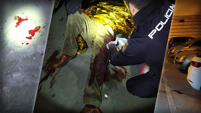 Un policía atiende al herido, que sangra abundantemente por la pierna.