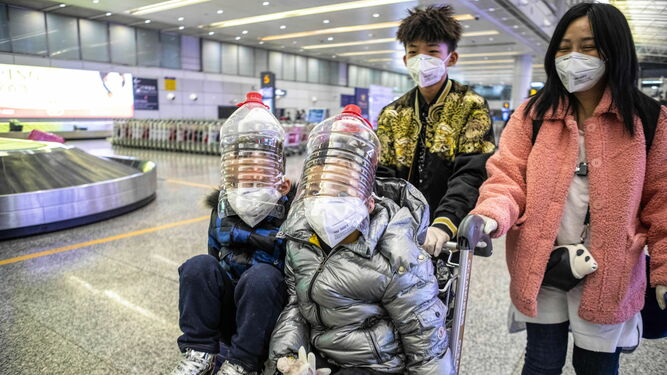 Una familia china con dos niños cuyas cabezas están protegidas por botellas de agua