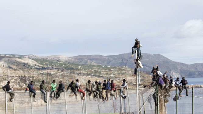 Inmigrantes de origen subsahariano encaramados en la parte alta de la valla de Melilla  en abril de 2014.
