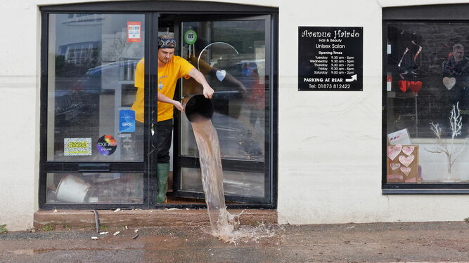 Un joven vacía un cubo mientras limpia su tienda en la localidad galesa de Crickhowell (Gales).