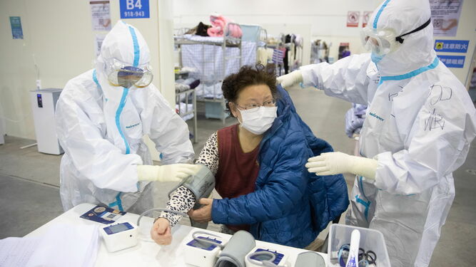 Una mujer es atendida por dos especialistas en un hospital de Wuhan.