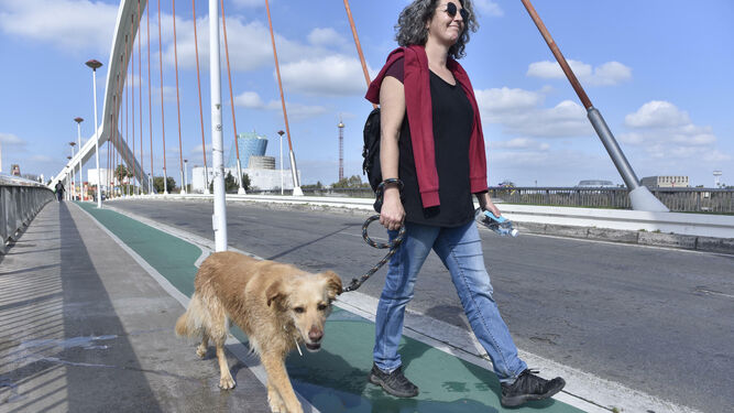 Una mujer camina junto a su perro por el Puente de la Barqueta.