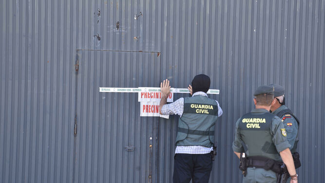 Varios agentes precintan las instalaciones de Magrudis, en el polígono industrial El Pino de Sevilla.