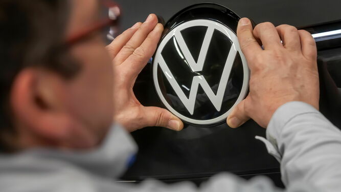 Un operario coloca el logotipo de Volkswagen en un coche