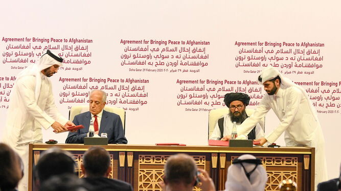 El representante de EEUU, Zalmay Khalilzad (izq.), y el mulá Abdul Ghani Baradar, en la firma del acuerdo en Doha.