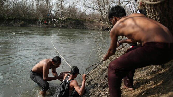 Refugiados regresan al lado turco de la frontera ayudados por una cuerda tras permanecer dos días en una pequeña isla del río Evros.