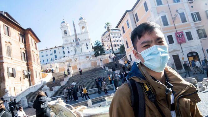 Un turista pasea con mascarilla por la Plaza de España en Roma (Italia)