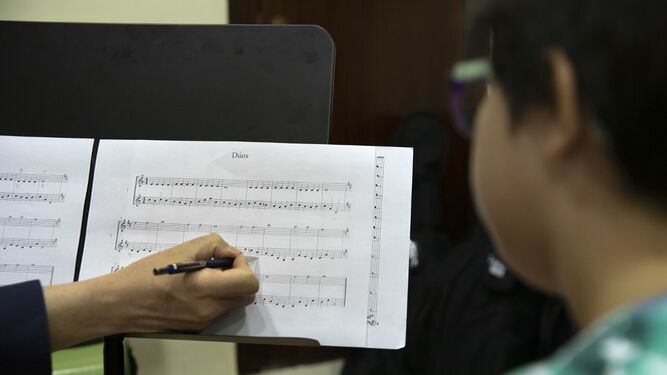 Un maestro enseña una partitura a un alumno.