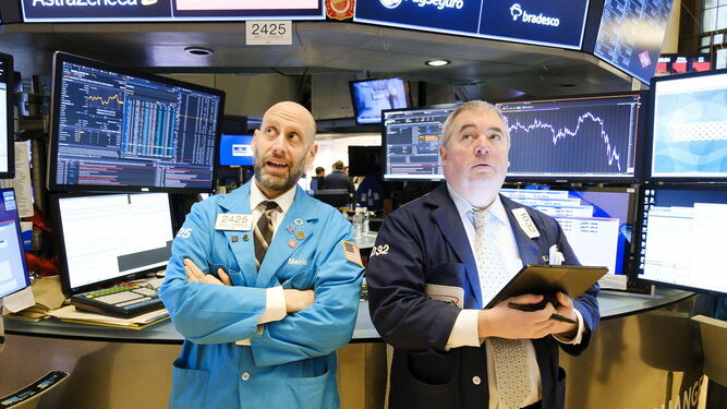 Dos agentes de bolsa de Wall Street miran preocupados la evolución de los indicadores por el coronavirus.