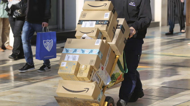 Un repartidor transporta varios paquetes de Amazon.