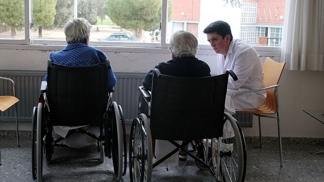 Dos ancianas con un cuidador en una residencia de la tercera edad.