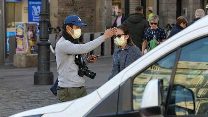 Una pareja de turistas pasea por Madrid con mascarilla