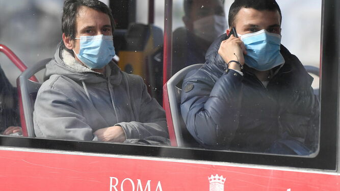 Dos personas con mascarillas en un autobús urbano