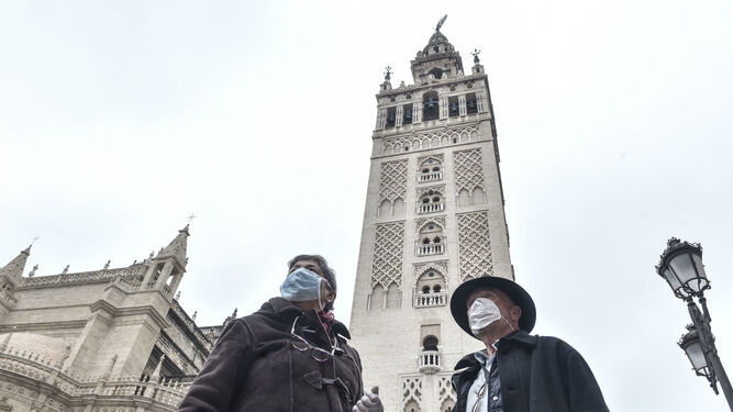 Dos turistas con mascarillas a los pies de la Giralda.