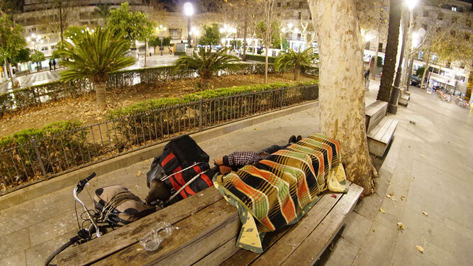 Un transeúnte duerme sobre un banco de la Plaza Nueva.