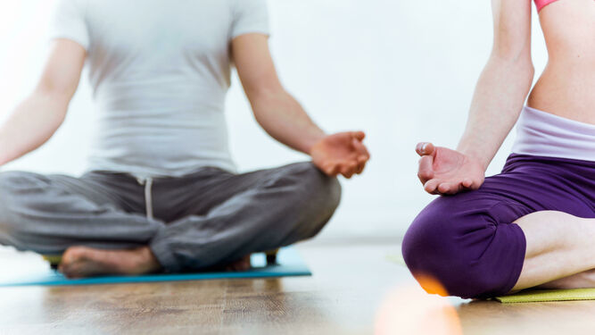 Dos jóvenes practican yoga en casa.
