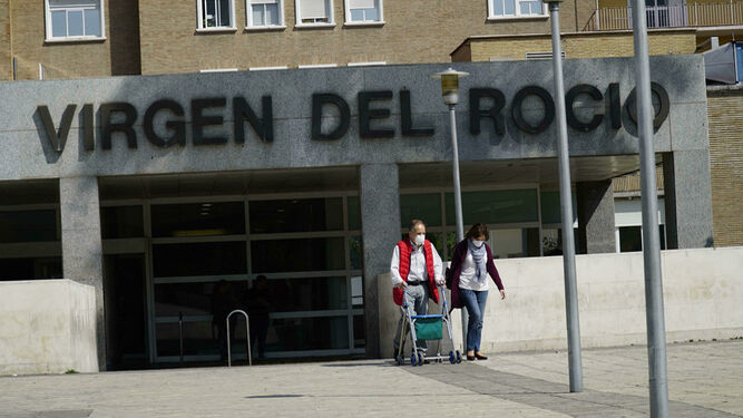 Dos personas salen del Hospital Virgen del Rocío con mascarillas.