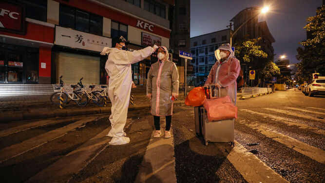 Un voluntario toma la temperatura a una mujer embarazada antes de entrar en un hospital de Hubei.