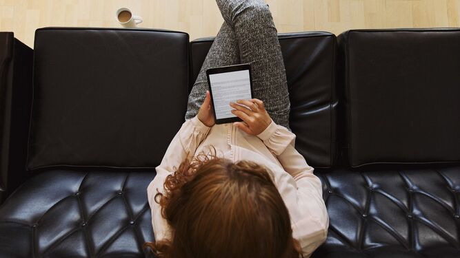Una mujer lee en un dispositivo electrónico.