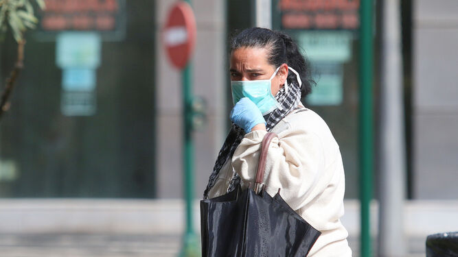 Una mujer se protege con mascarilla y guantes para evitar contagiarse de coronavirus.
