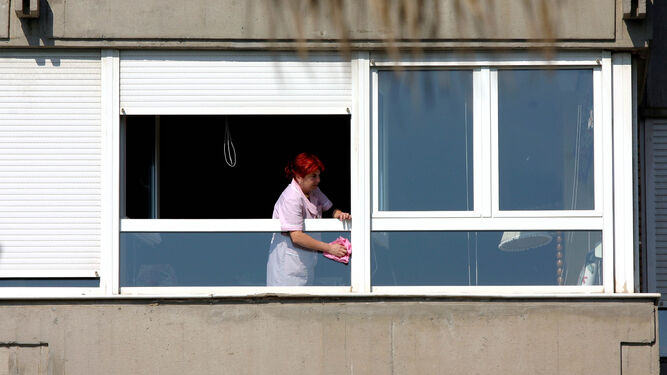 Una empleada de hogar limpia una ventana